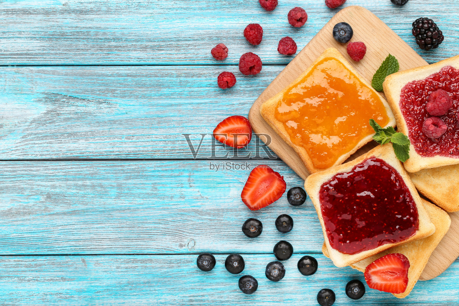 在蓝色的木桌上，用果酱和切菜板敬酒照片摄影图片