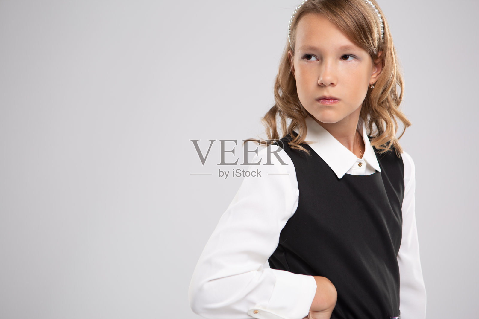 一个沮丧的女学生的肖像，站着她的手在她的臀部和看着远处的白色背景照片摄影图片