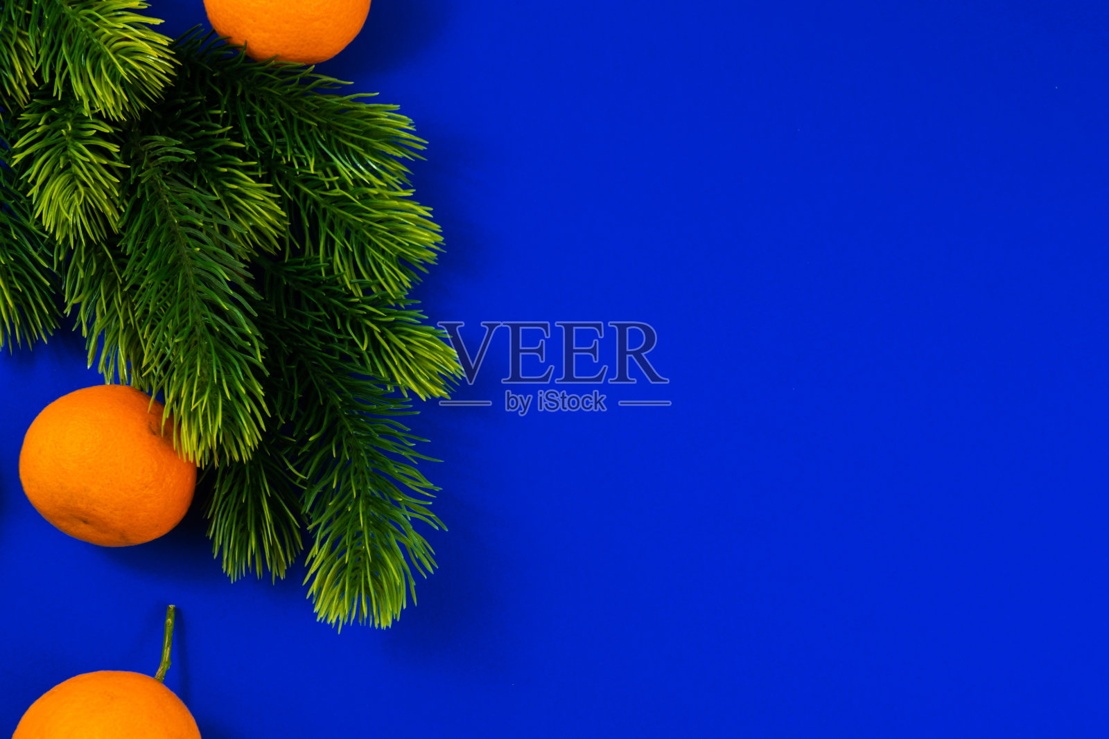 圣诞和假日构图接近，冷杉树枝和桔子在蓝色的背景和复制空间照片摄影图片