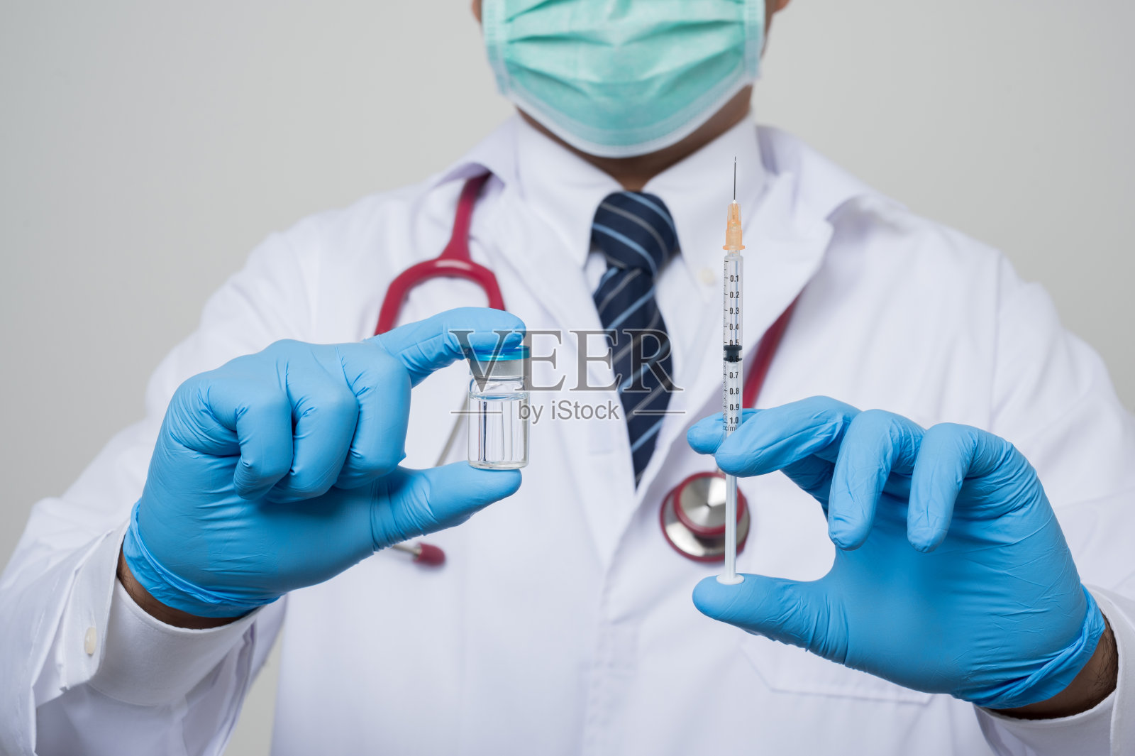 近距离观察亚洲秃顶医生，白大褂，听诊器，蓝色手套，拿着一个“疫苗瓶和注射器隔离在白色背景。”照片摄影图片