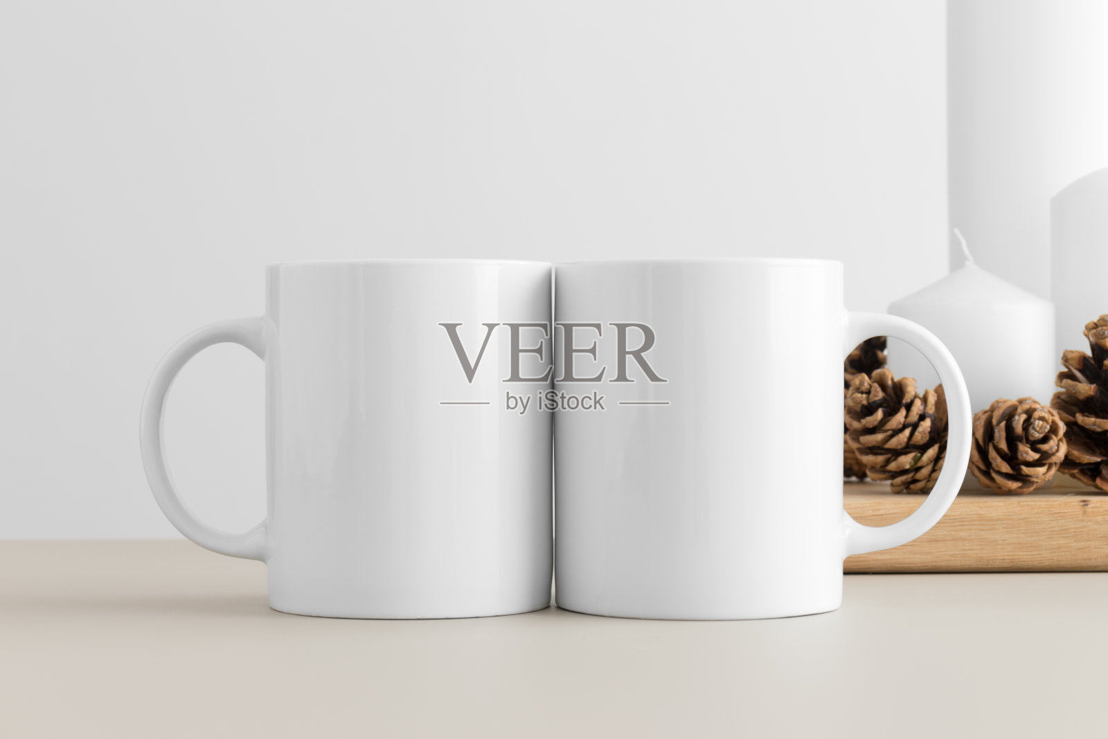 桌子上放着两支蜡烛的白色马克杯模型。圣诞装饰照片摄影图片