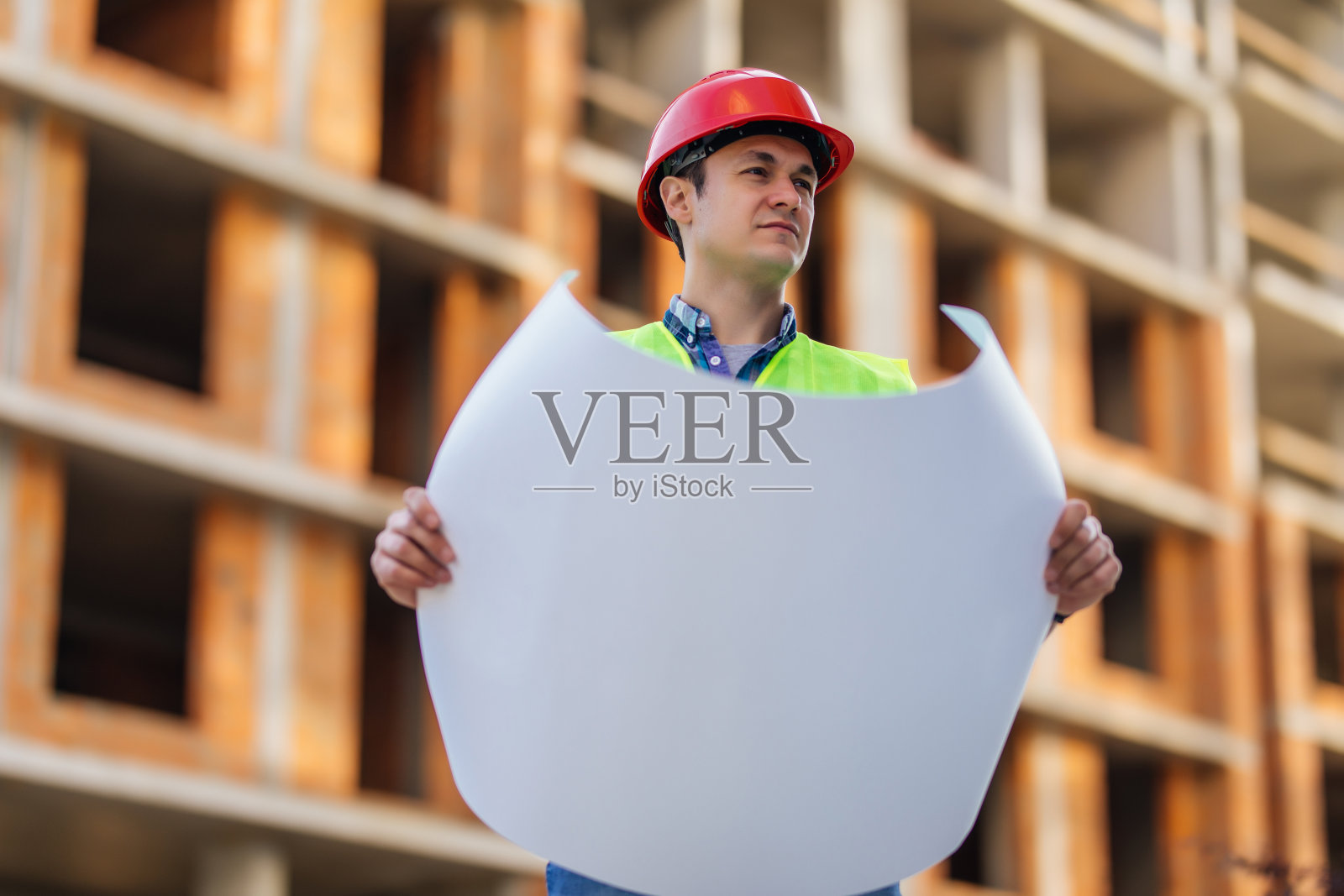 一个拿着设计图在建筑工地工作的年轻工程师照片摄影图片