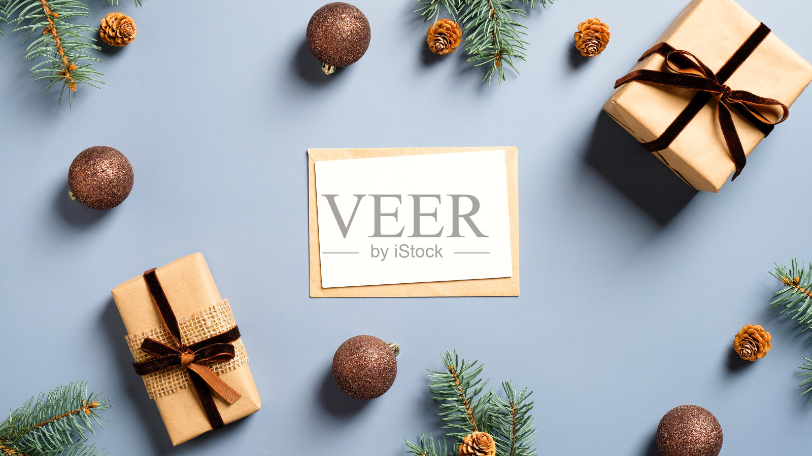 空白圣诞卡模型，信封，圣诞礼物，装饰品，松枝在淡蓝色的背景。平躺，俯视图。圣诞节、新年、寒假概念。照片摄影图片