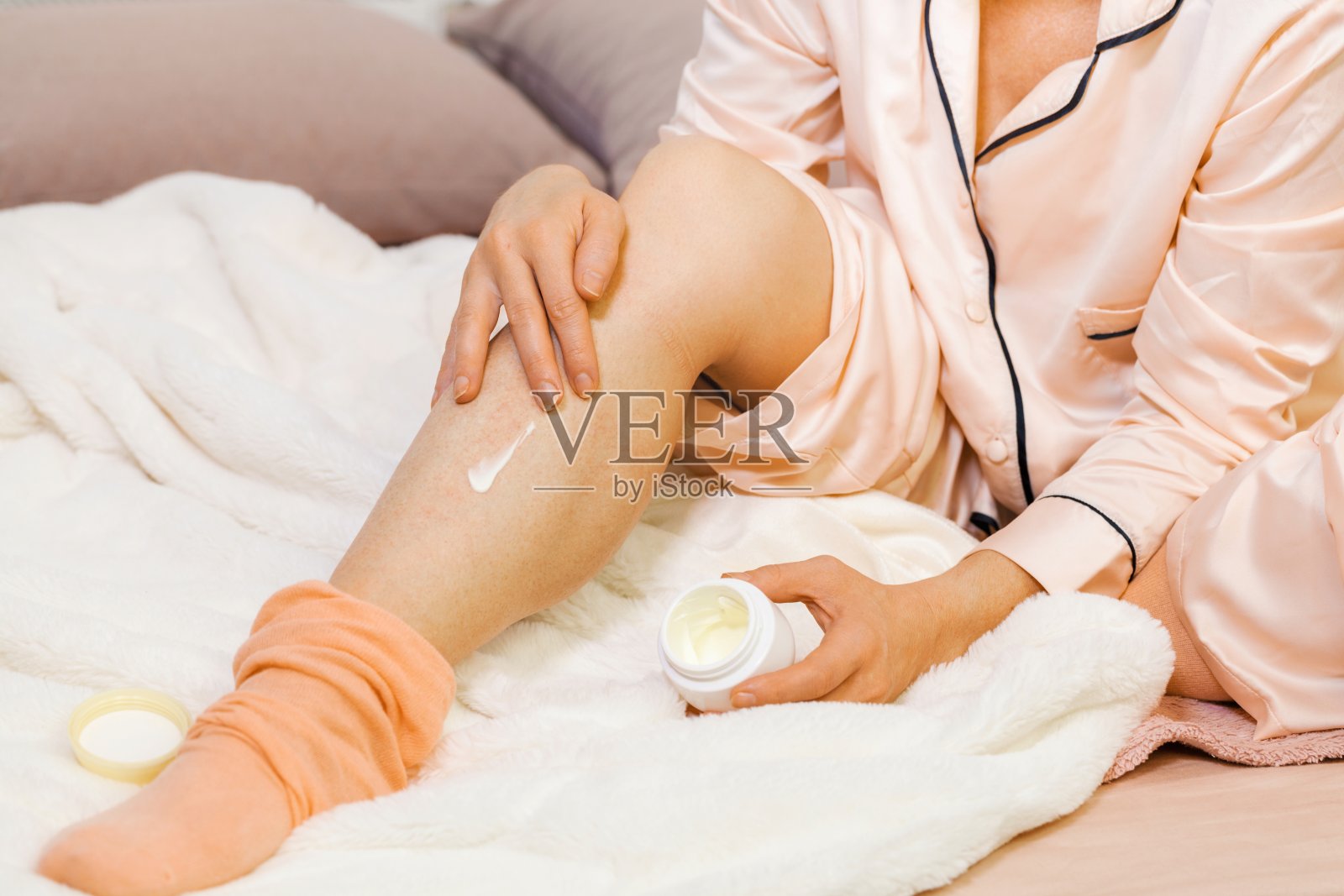 妇女为腿部发痒涂抹霜。过敏和皮肤病的概念照片摄影图片