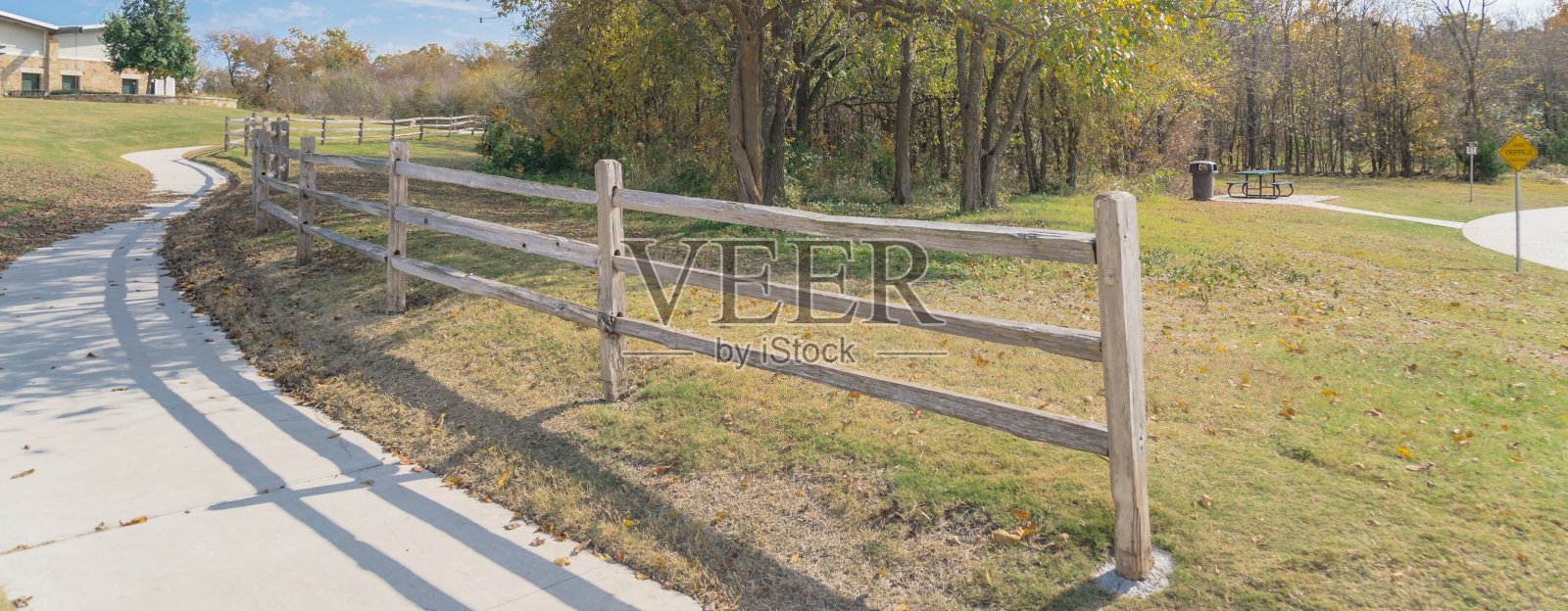 在美国德克萨斯州的公园里，带有木制栅栏的弯曲混凝土路径全景照片摄影图片
