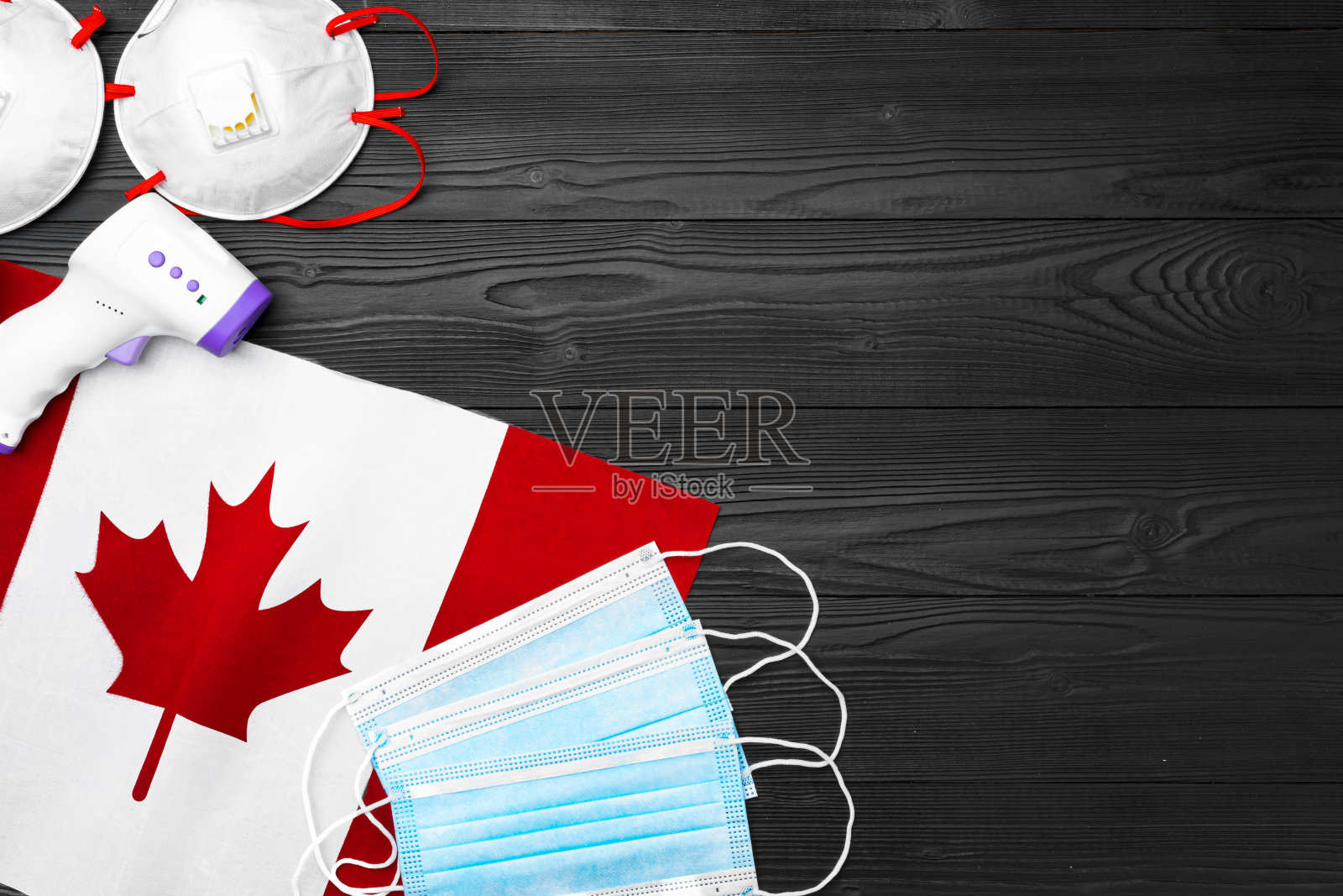 加拿大国旗上的医用口罩和非接触式温度计照片摄影图片