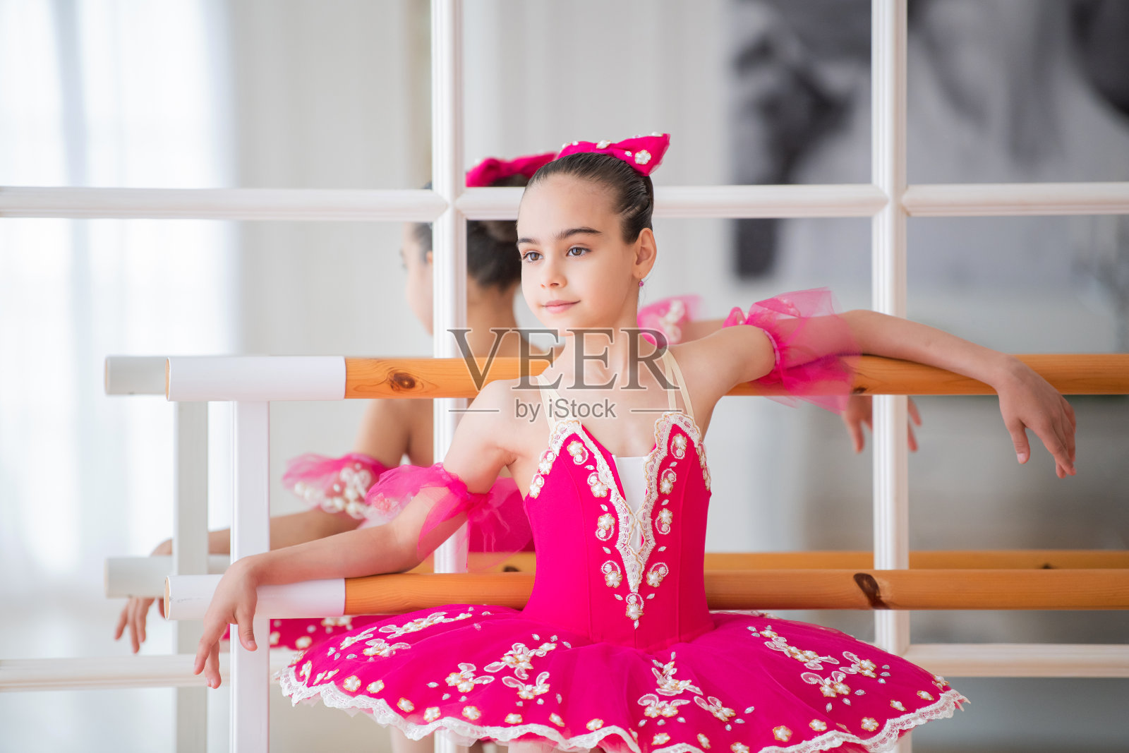 一个穿着明亮的芭蕾舞裙的小芭蕾舞女演员站在机器前的镜子前照片摄影图片