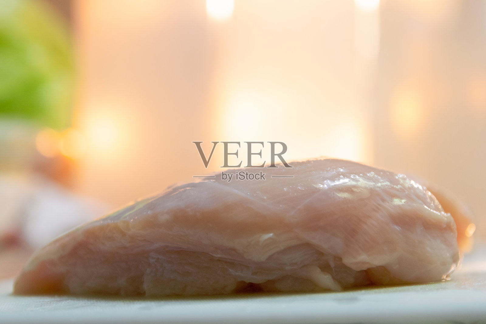 去皮的鸡胸肉放在砧板上，厨房里有自然光。照片摄影图片