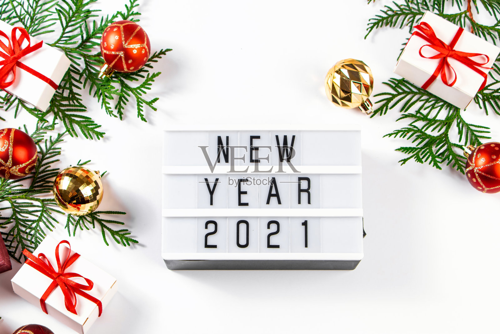 2021年新年作文。白色背景上有红色丝带和金色圣诞球的礼盒。照片摄影图片