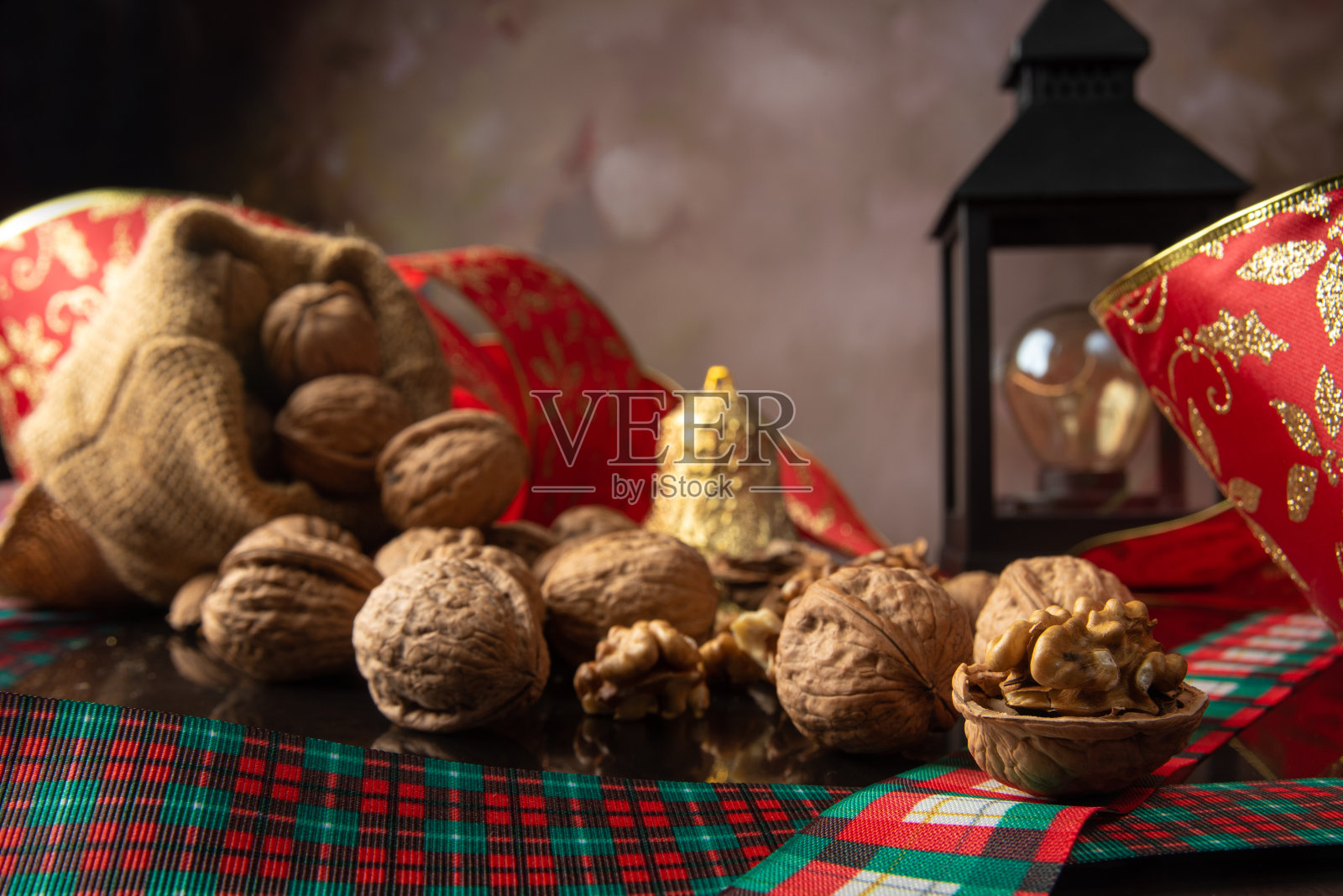 坚果，坚果的细节与圣诞丝带和灯笼分散在一个反射的黑色表面，抽象的背景，选择性焦点。照片摄影图片