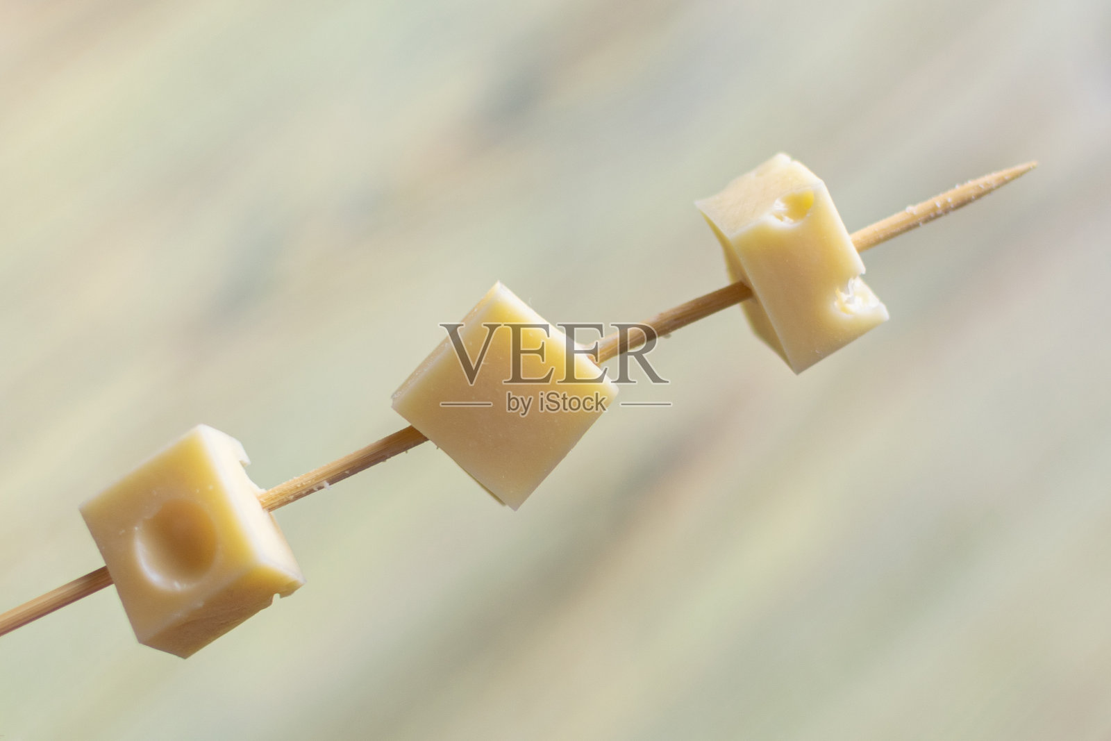 木头背景上的烤肉串上的奶酪块。照片摄影图片