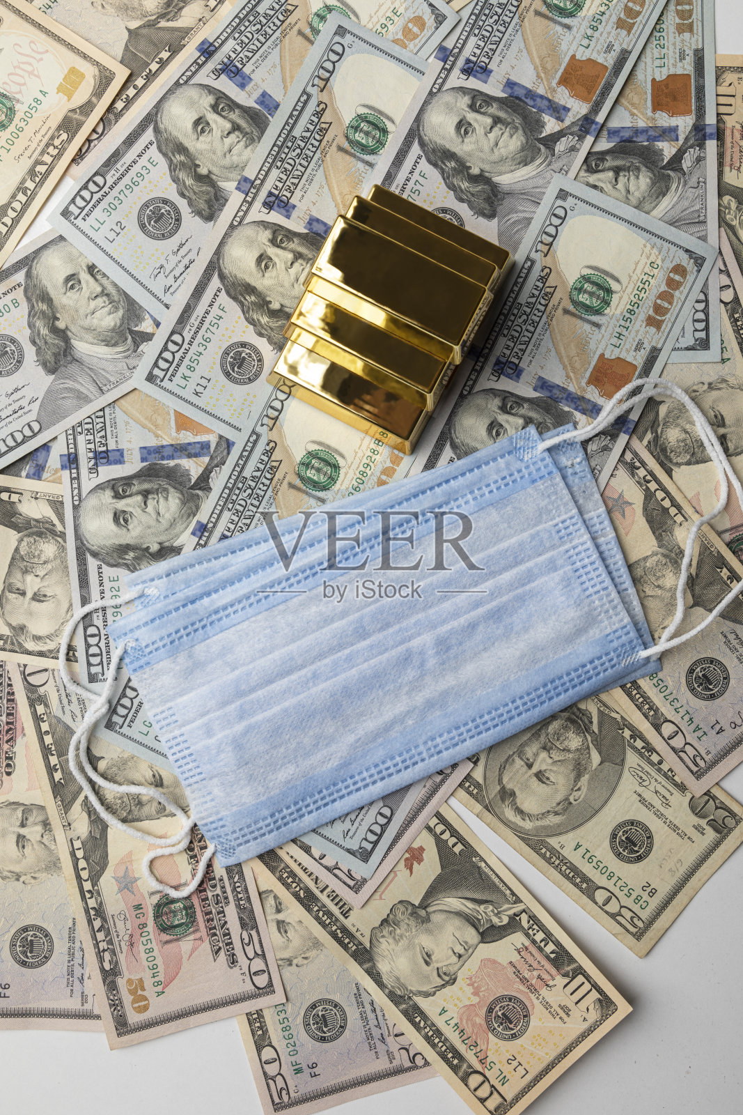 在新冠肺炎疫情危机期间，美元纸币上印有金条和医用防护口罩照片摄影图片