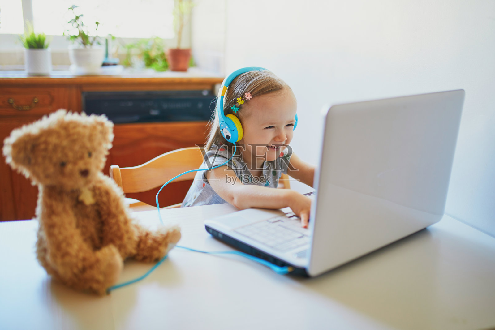 蹒跚学步的小女孩戴着手机和笔记本电脑照片摄影图片