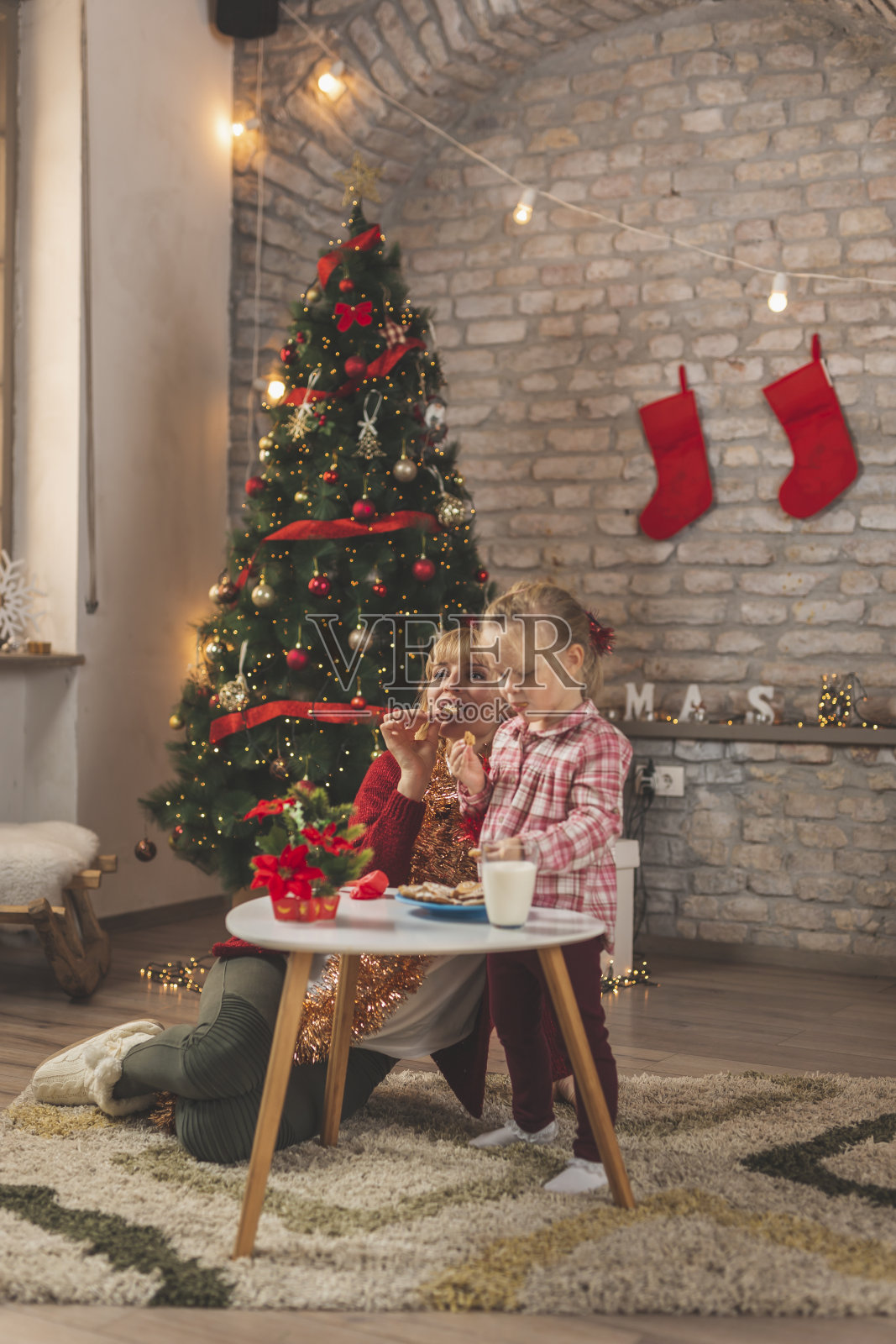 妈妈和女儿吃着圣诞饼干，喝着牛奶照片摄影图片