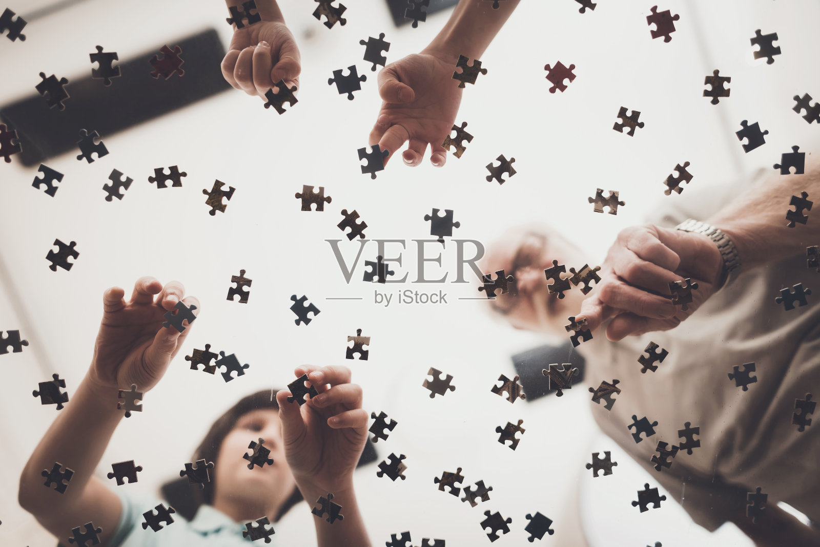 爷爷、孙子、孙女在家。爷爷和孩子们在玩拼图游戏。照片摄影图片