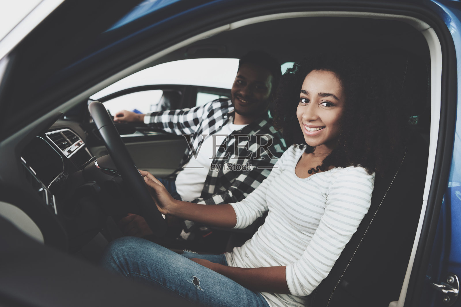 非裔美国家庭在汽车经销商。妈妈和爸爸坐在一辆新车里。照片摄影图片