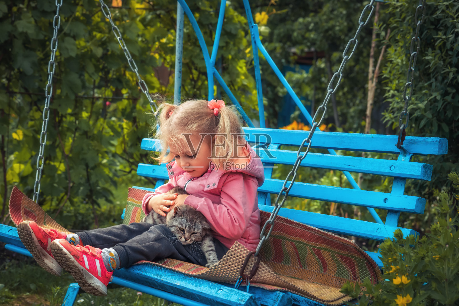 漂亮的孩子女孩在秋千上玩累猫户外概念宠物照顾照片摄影图片