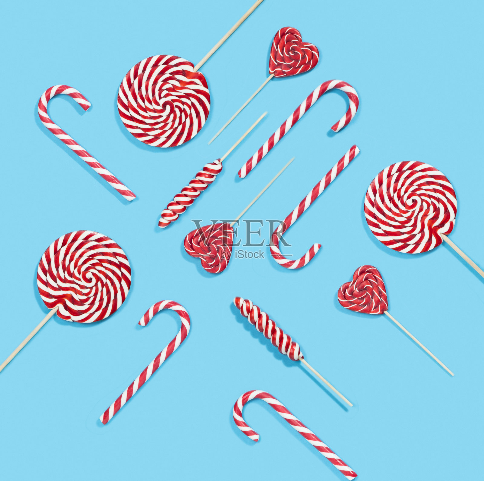 蓝色背景上的圣诞红色拐杖糖和棒棒糖图案插画图片素材