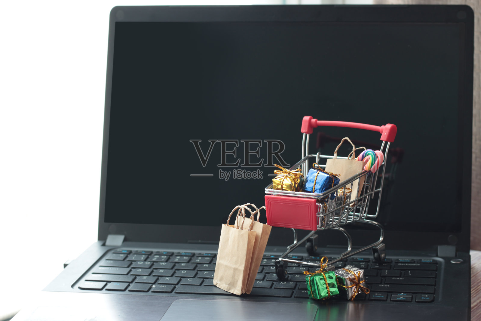 购物车购物袋，圣诞装饰品和礼品盒上的笔记本键盘。网上购物的圣诞节，电子商务业务和购买的商品从卖方通过互联网的概念为圣诞节，冬季和新年庆祝照片摄影图片