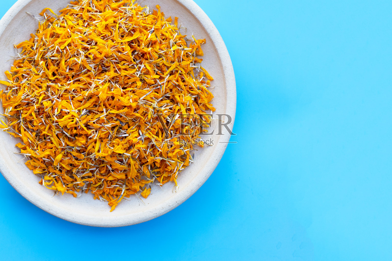 蓝色背景上的万寿菊花瓣。照片摄影图片