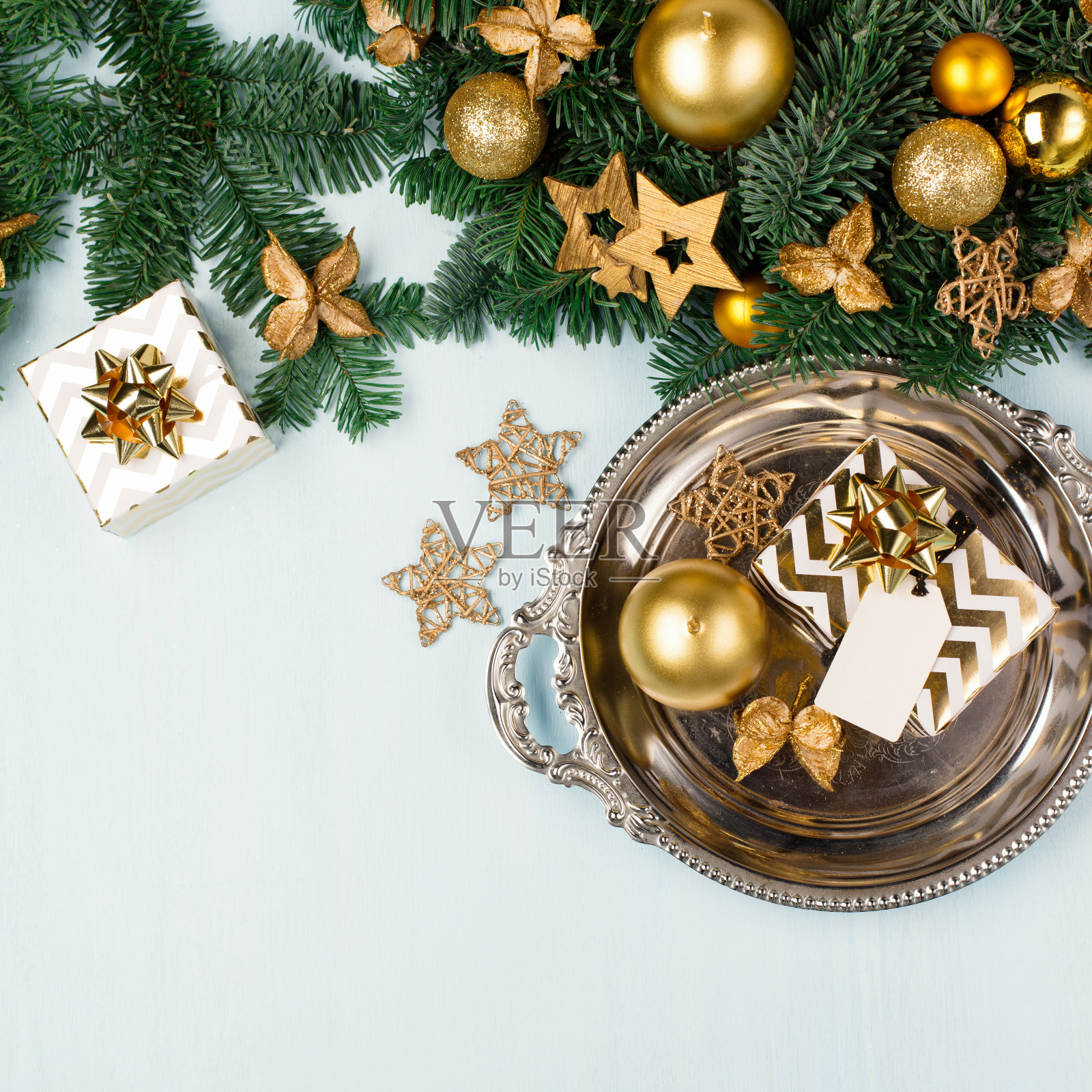 现代圣诞花圈与金色的蜡烛，绿色的树枝和金色的礼盒在蓝色的背景。寒假来临时间。照片摄影图片