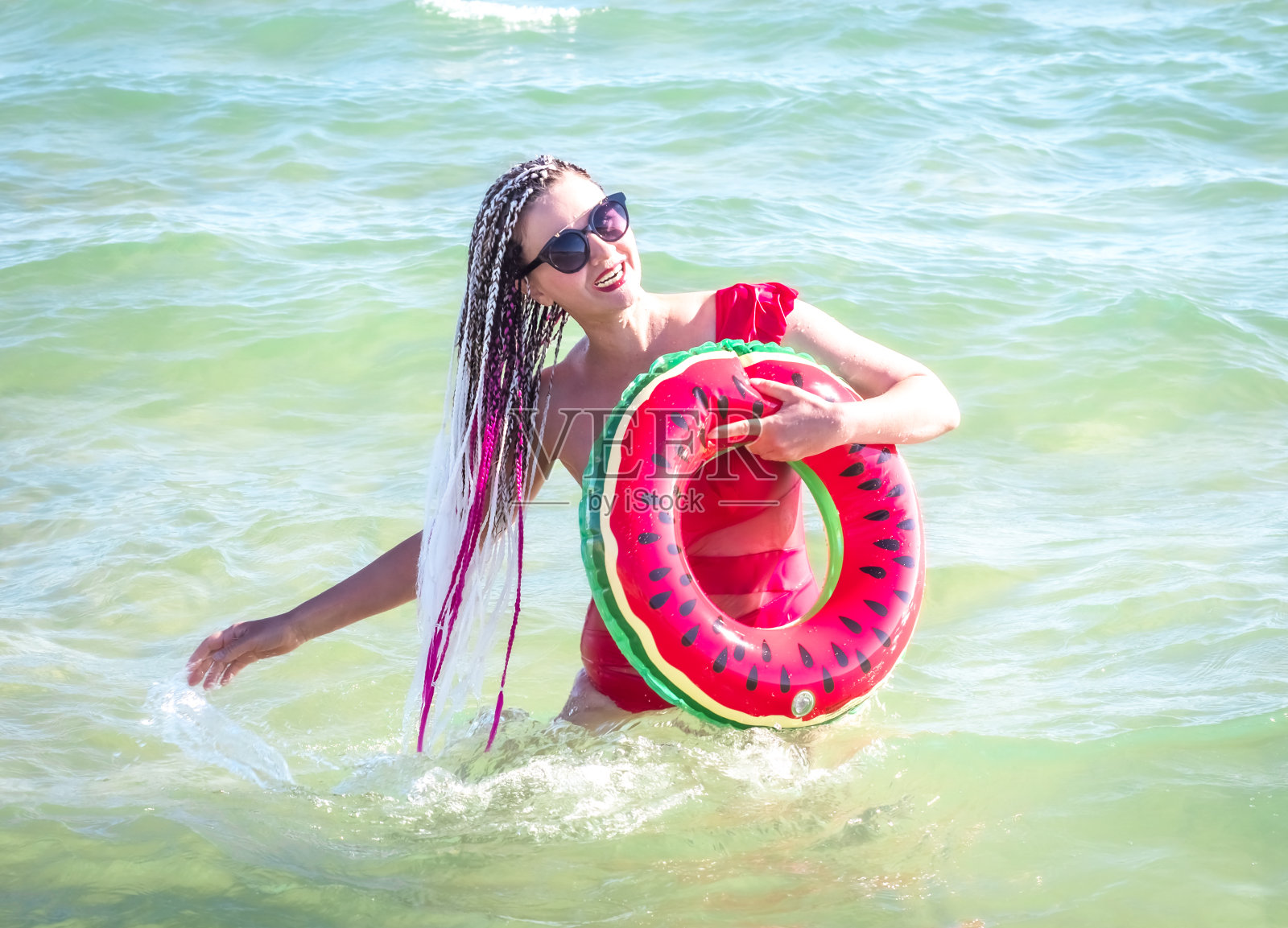 一个欢快的中年妇女拿着西瓜楔在海里游了一圈。休闲娱乐的概念照片摄影图片