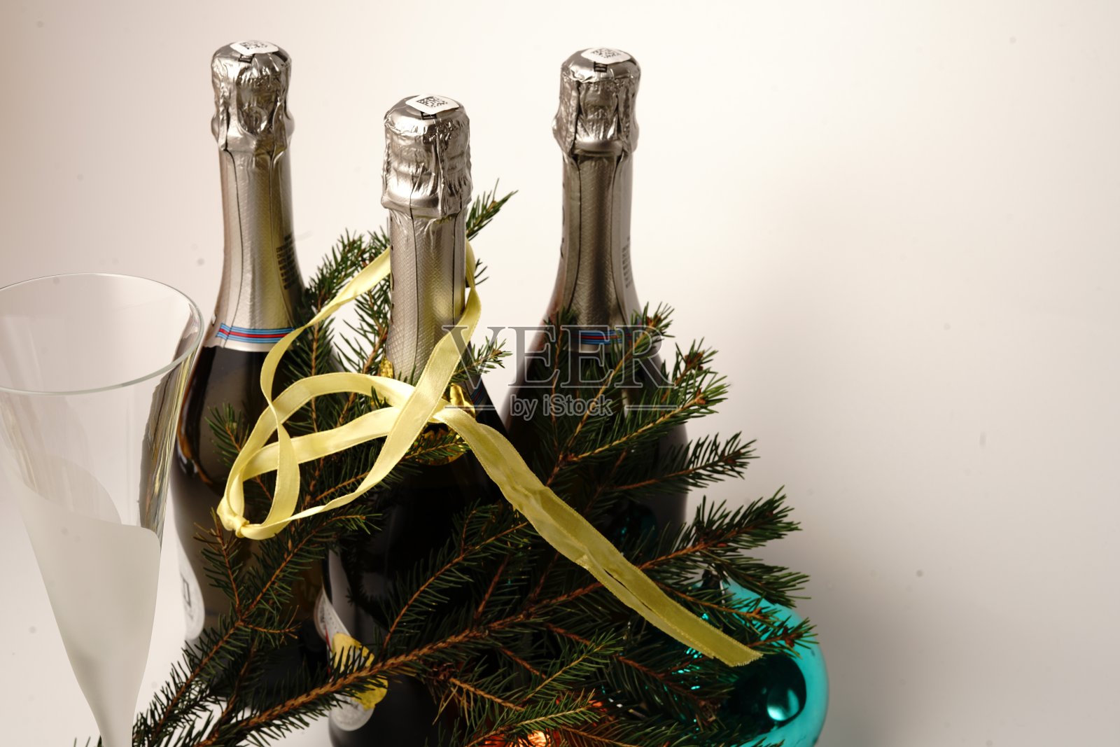白色背景上的香槟酒瓶。围绕着圣诞树的树枝和圣诞玩具。照片摄影图片