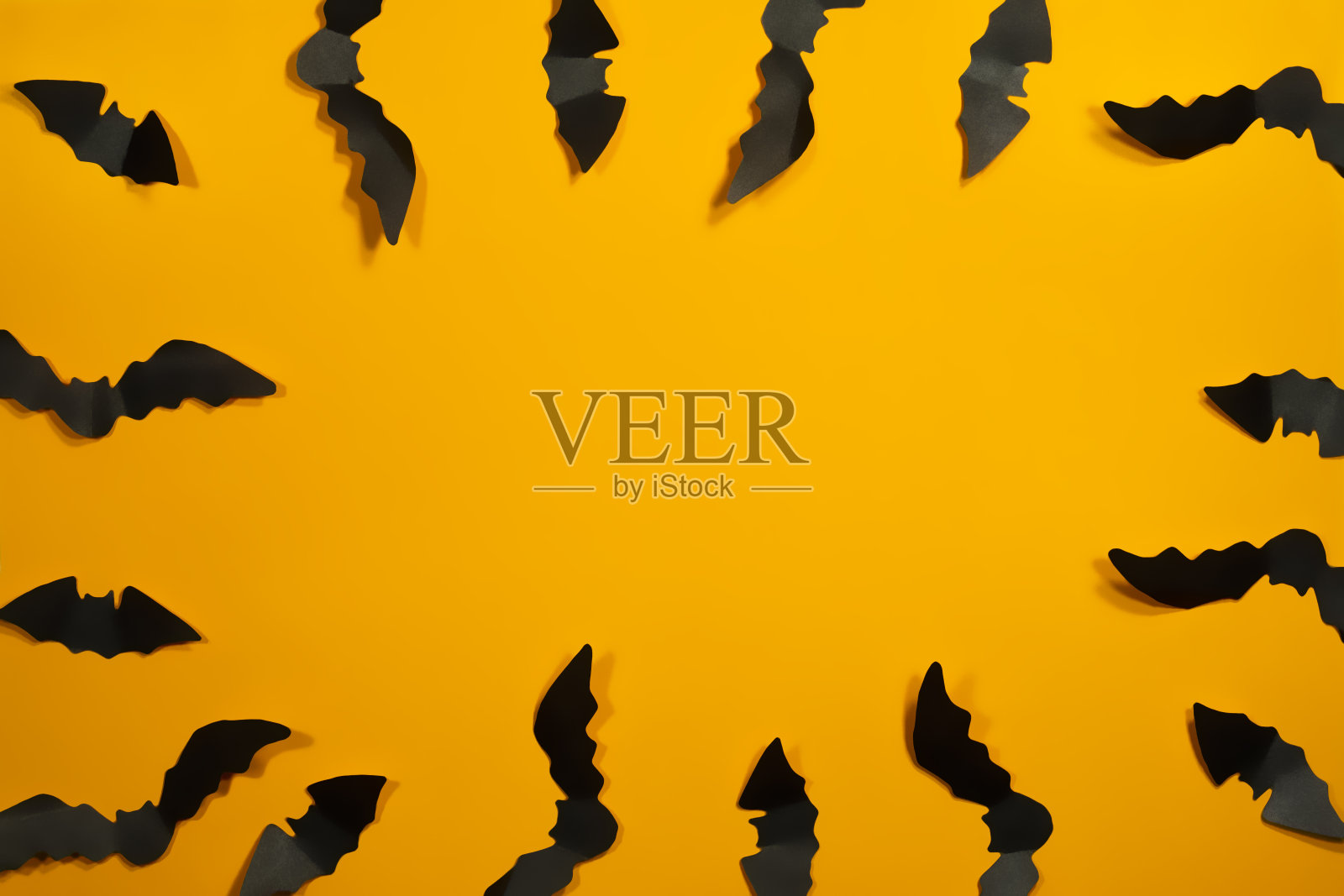 万圣节纸装饰概念。橙色背景上的黑色纸蝙蝠。万圣节的概念。照片摄影图片