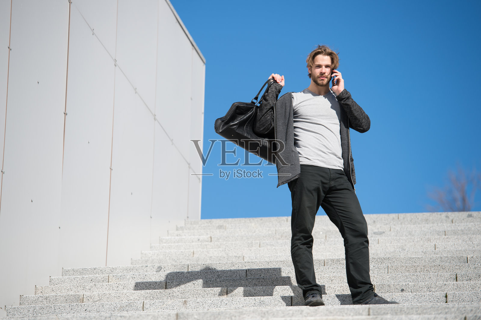 蓝天下，男人在楼梯上打电话照片摄影图片