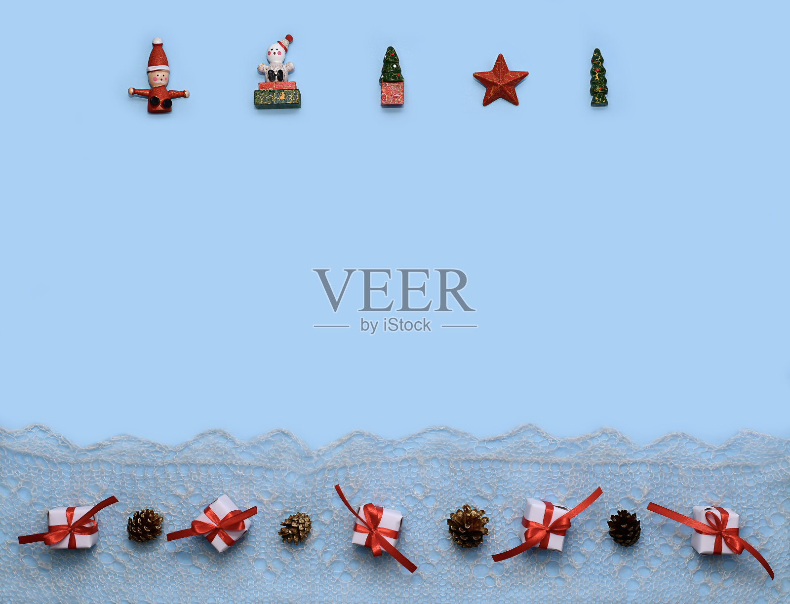 蓝色背景上的圣诞布局。上面是一个红绿白的小雕像。在楼下买礼物和甜筒。照片摄影图片