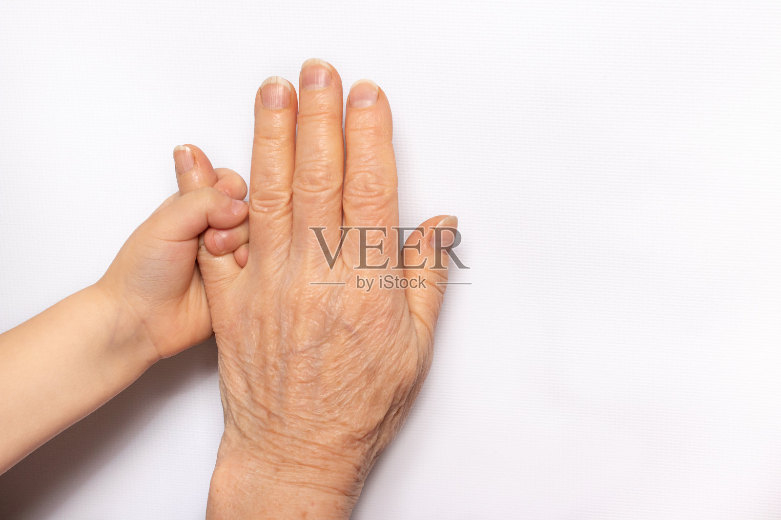 小孩子的手在一个老祖母的手里。老年与童年，祖母与孙子的交流，衰老，生命照片摄影图片