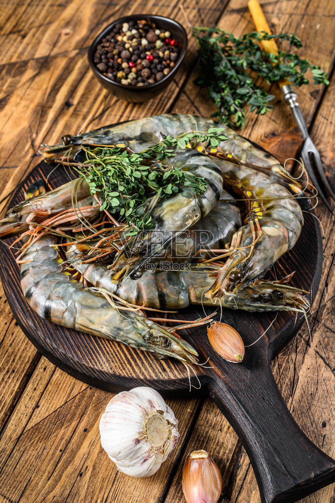 生的黑虎虾和香草放在砧板上。木制背景。俯视图照片摄影图片