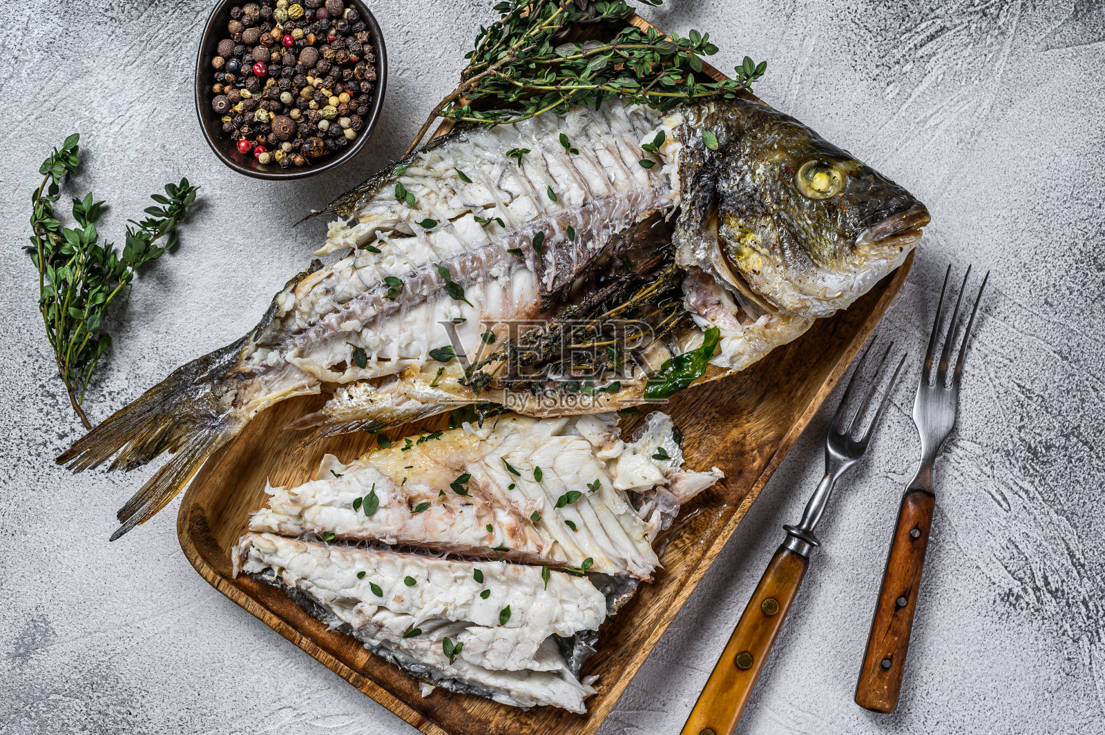 切好烤海鲷鱼放在木托盘里。白色背景。俯视图照片摄影图片