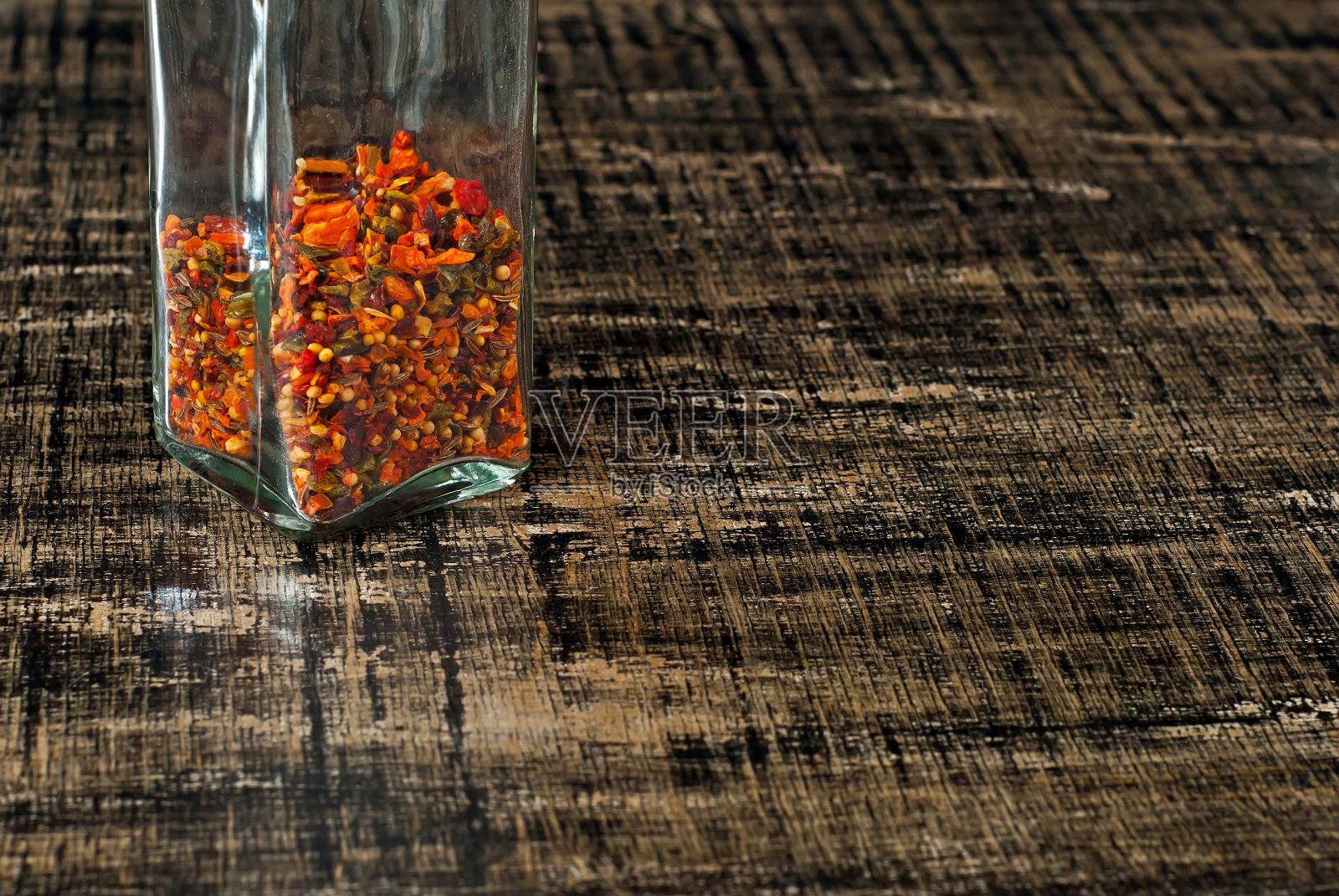 各种香料的混合物在一个玻璃罐中闭合。在一块又黑又旧的木板上放着香料和调味品。免费空间和复制空间的文本附近的调味品。照片摄影图片