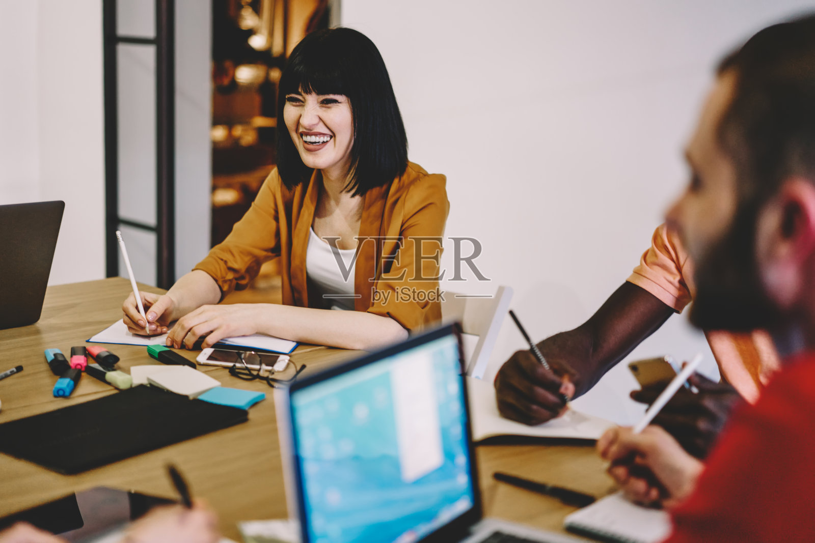 积极的女设计师与同事一起在办公室进行头脑风暴会议。愉快的年轻人穿着时髦的休闲装，在创业项目的合作中玩得很开心照片摄影图片