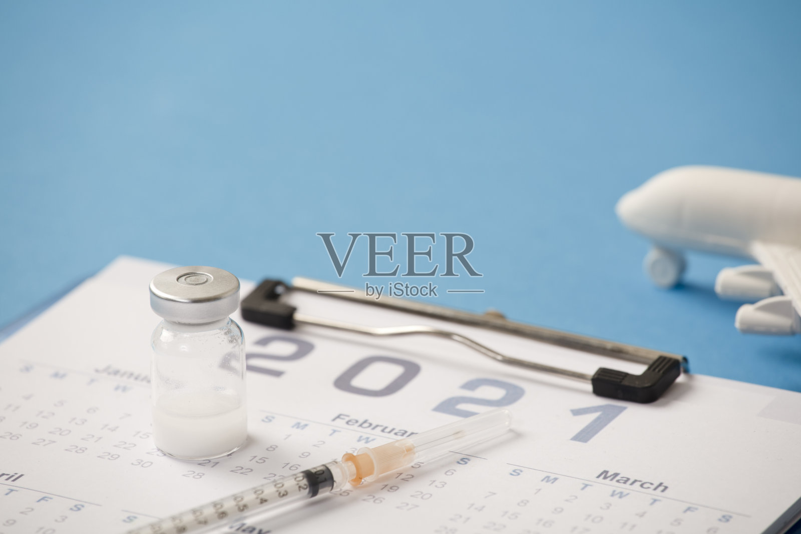 疫苗和注射器，日历2021年，白色平面，蓝色背景照片摄影图片