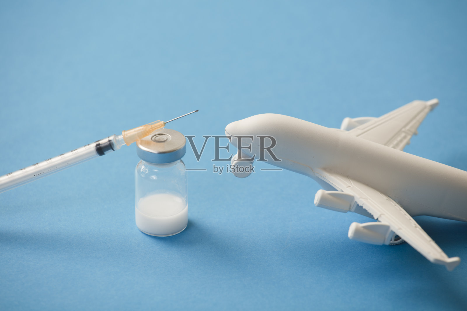 带注射器的疫苗筒，白色平面，蓝色背景照片摄影图片