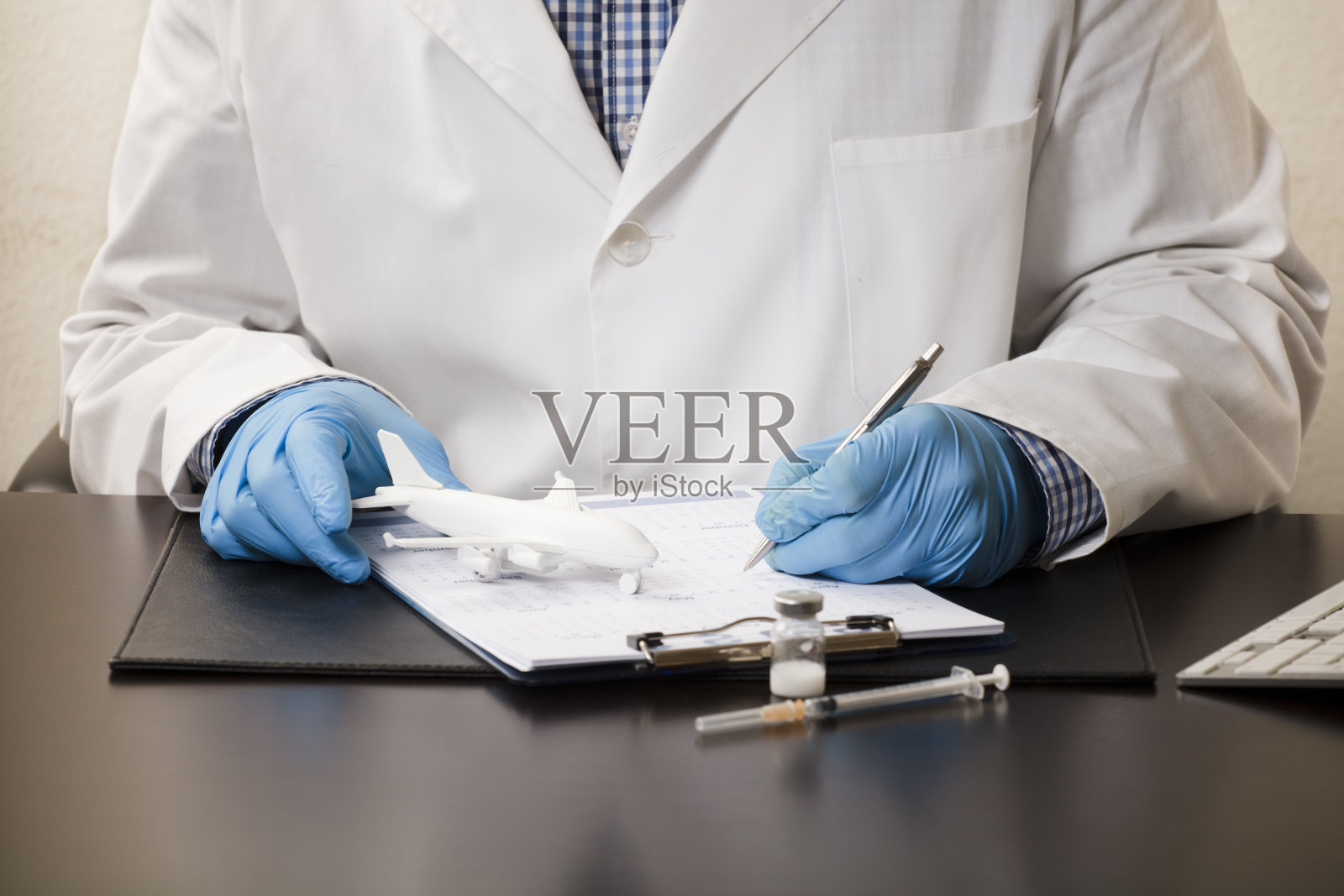 医生的手用笔填写数据，在表格上，用白色的平面，注射器，电脑键盘，在工作台上，白色的背景。照片摄影图片