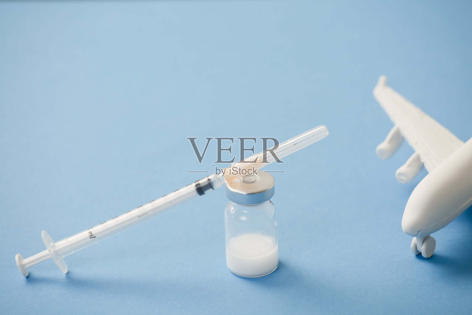 带注射器的疫苗筒，白色平面，蓝色背景照片摄影图片