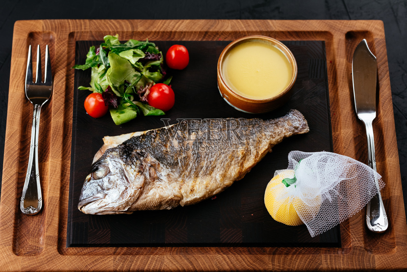 烤鲷鱼配蔬菜，黑色背景照片摄影图片