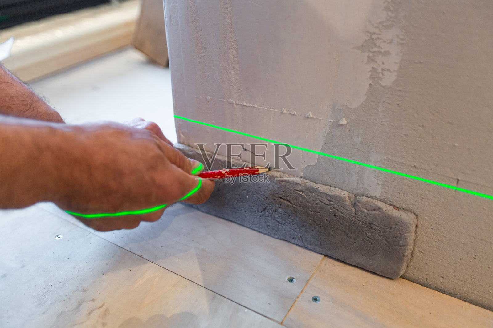 建筑商在正在建设、改造、翻新、大修、扩建、修复和重建的公寓中使用激光施工水平。家居改善或装修的概念照片摄影图片