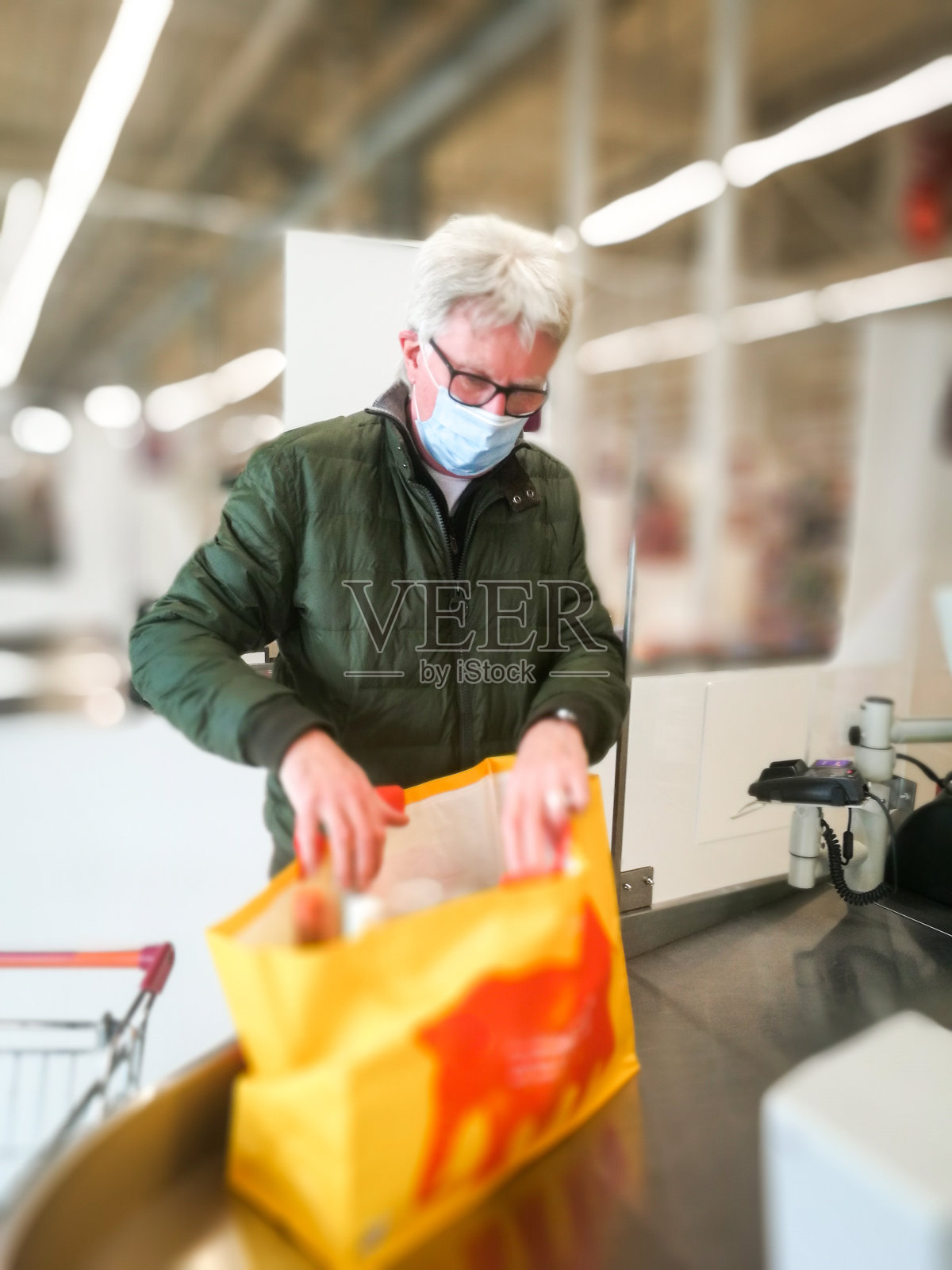 戴着防护口罩的老人在超市结账处照片摄影图片