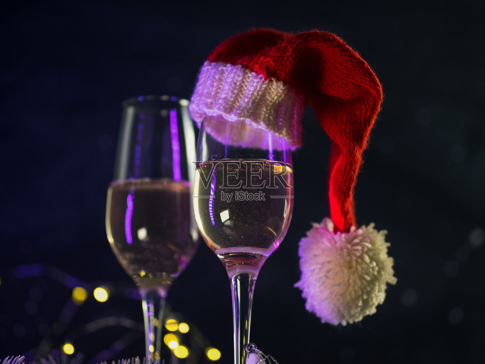 庆祝2021年的圣诞节。两杯香槟，戴着圣诞老人的帽子，背景是黑色的照片摄影图片