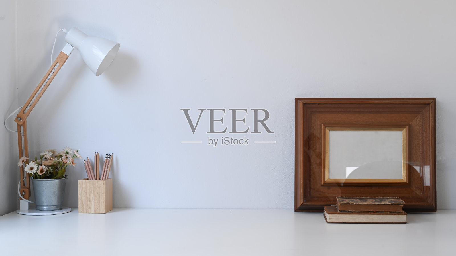 复古的工作空间，框架，铅笔，盆栽植物，咖啡杯，台灯和旧书在白色的桌子上。照片摄影图片