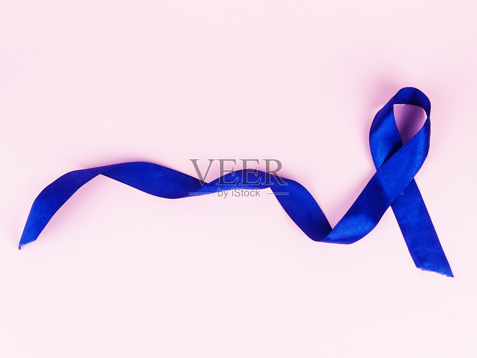 粉色背景上的蓝丝带，俯视图。癌症的认识照片摄影图片