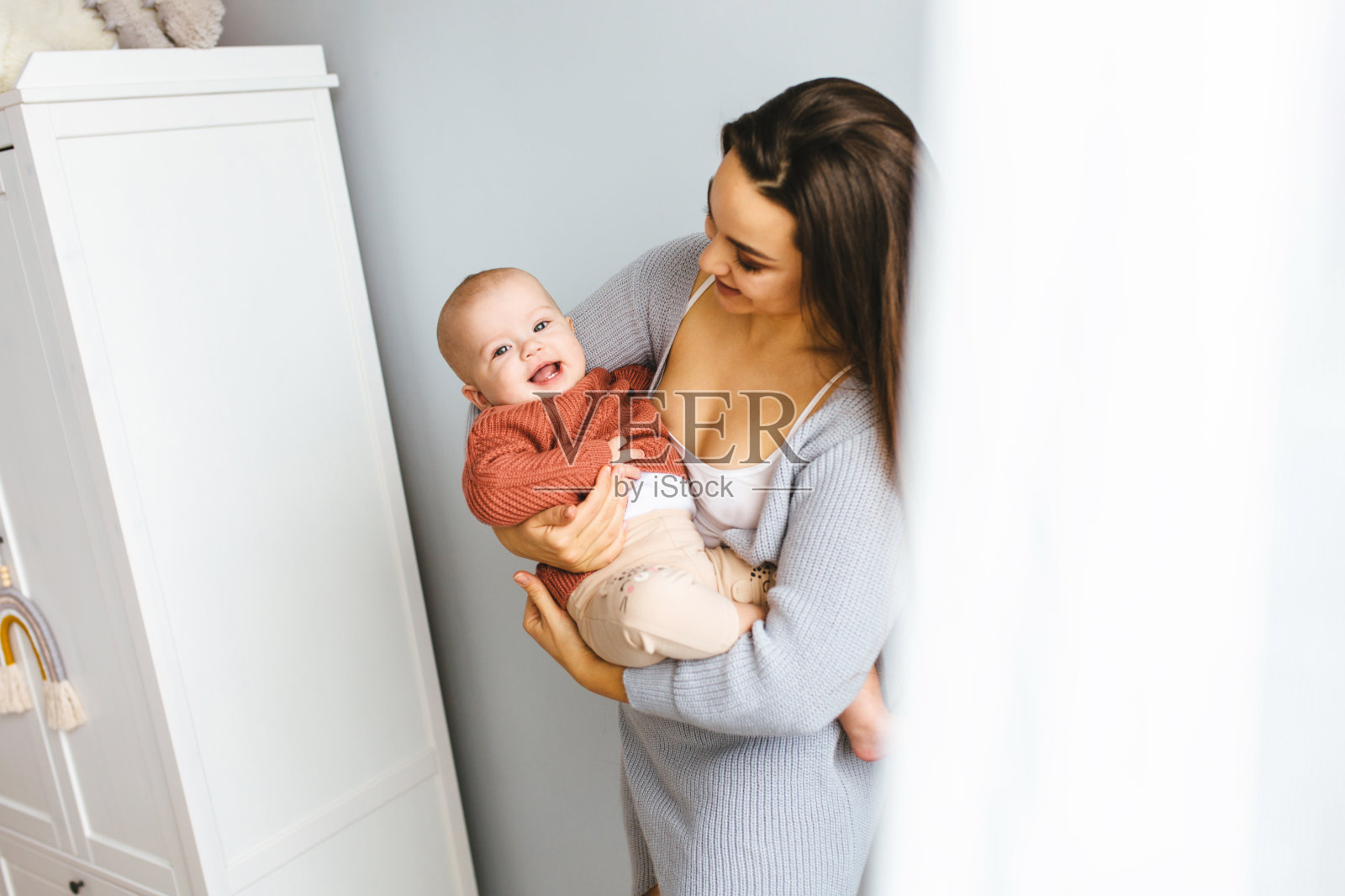 快乐的妈妈抱着她的宝贝女儿。年轻美丽的母亲抱着她的孩子，拥抱着，母亲的概念。照片摄影图片