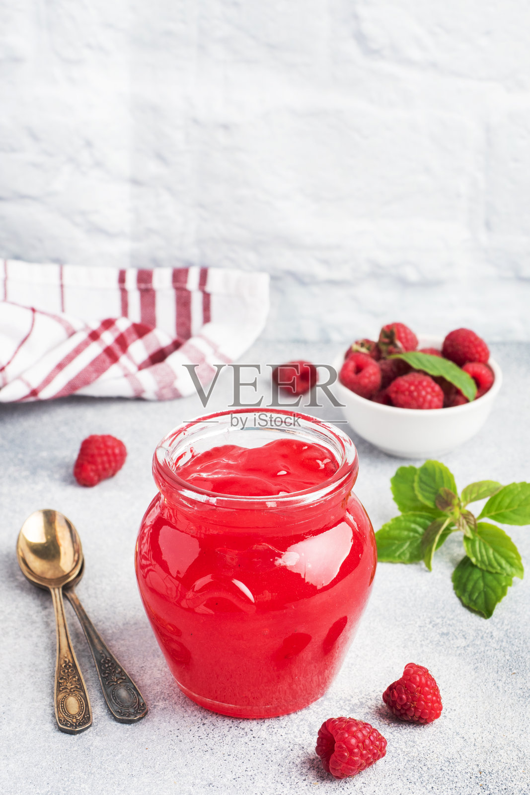 自制的覆盆子果酱装在玻璃罐中，新鲜的覆盆子和薄荷在灰色的混凝土背景上。本空间照片摄影图片