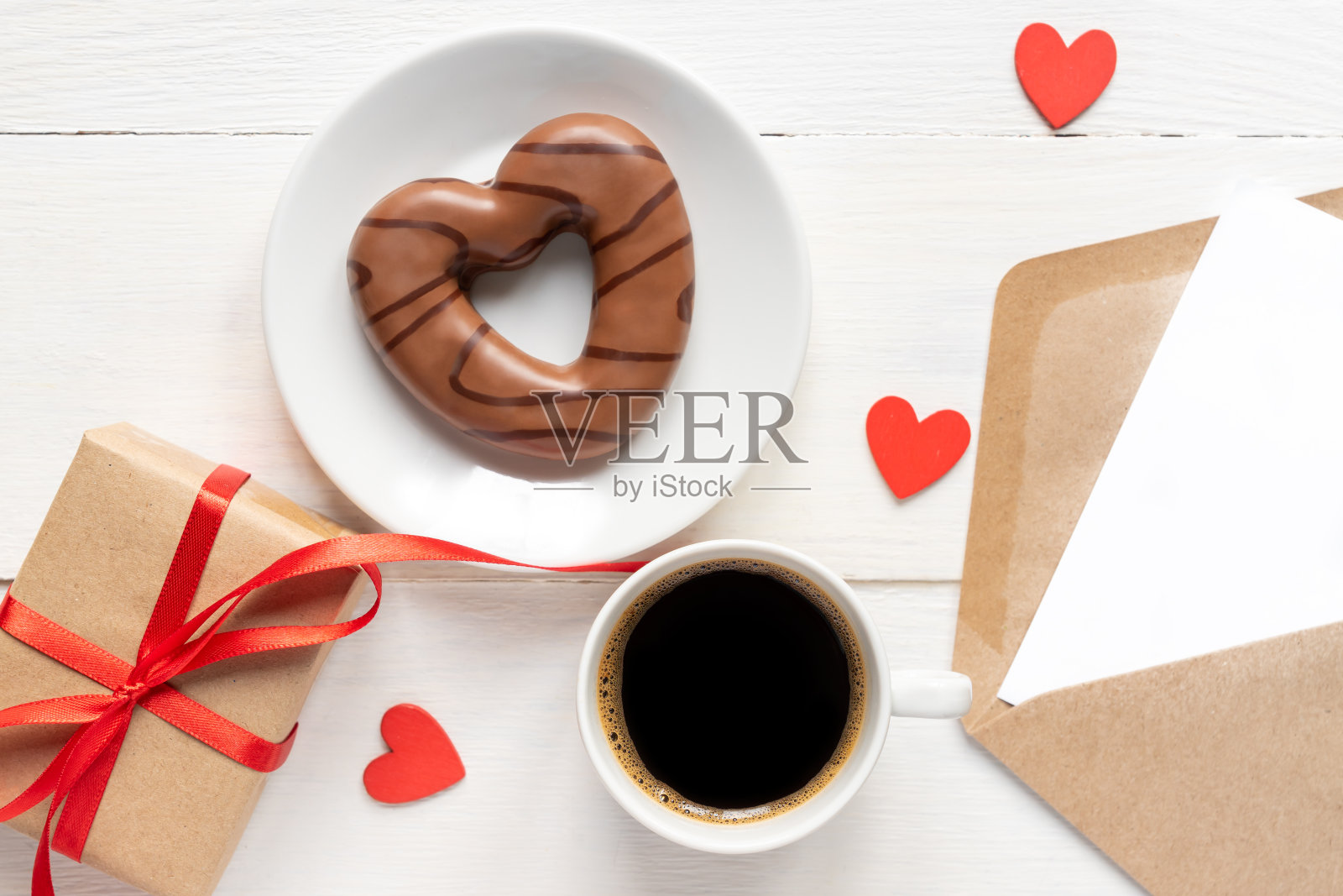 情人节模型。咖啡，心形巧克力饼干，礼品盒和纸卡与工艺信封在白色木制桌子上顶视图。平的风格。照片摄影图片