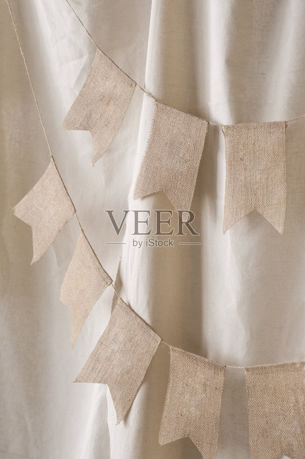 一个装饰旗帜花环的特写，以装饰在米色背景上的照片区。生日庆典的节日背景装饰。有选择性的重点照片摄影图片