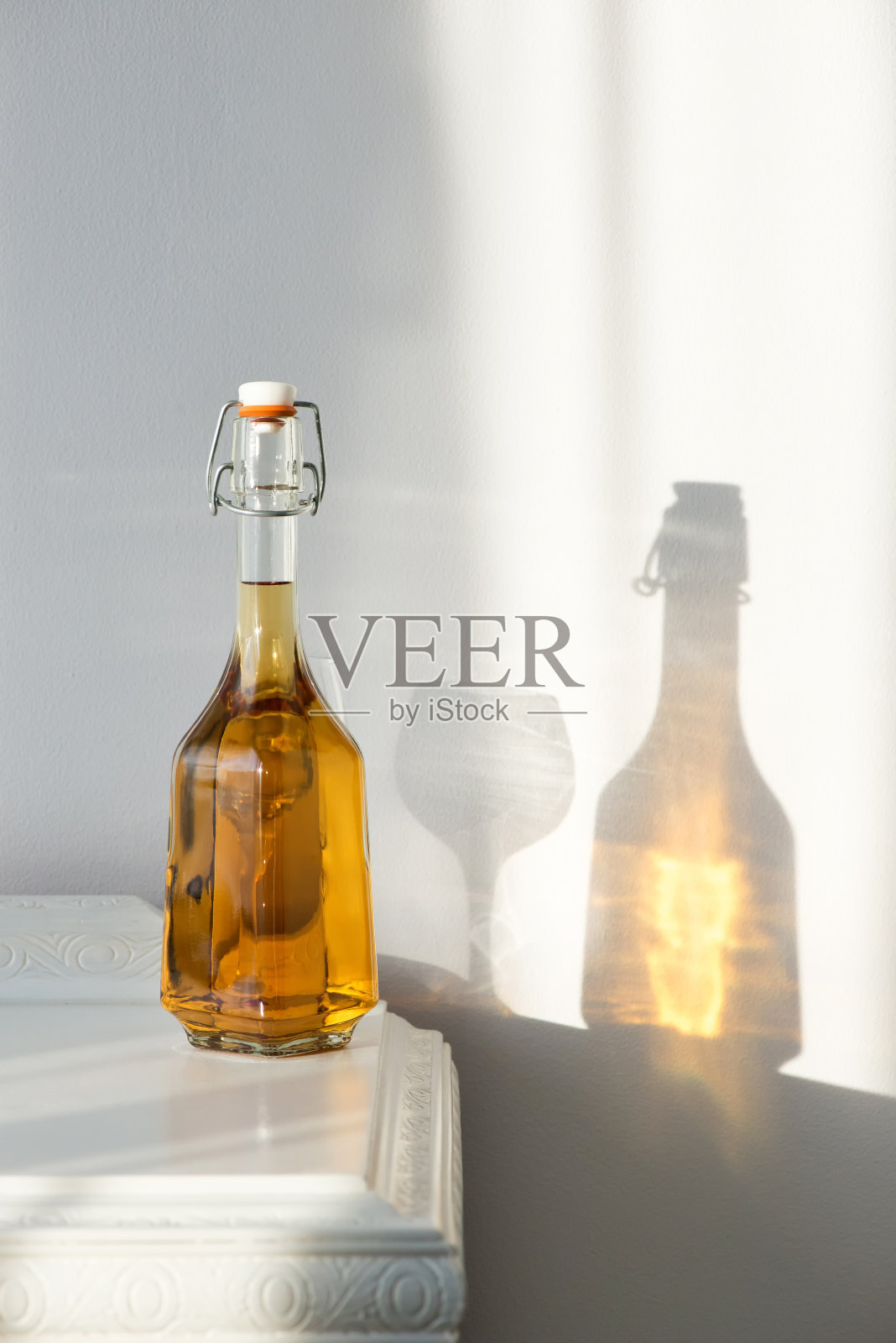 优雅的酒瓶与酒精和空玻璃杯在一个复古的橱柜和美丽的阳光反射在墙上-艺术概念照片摄影图片